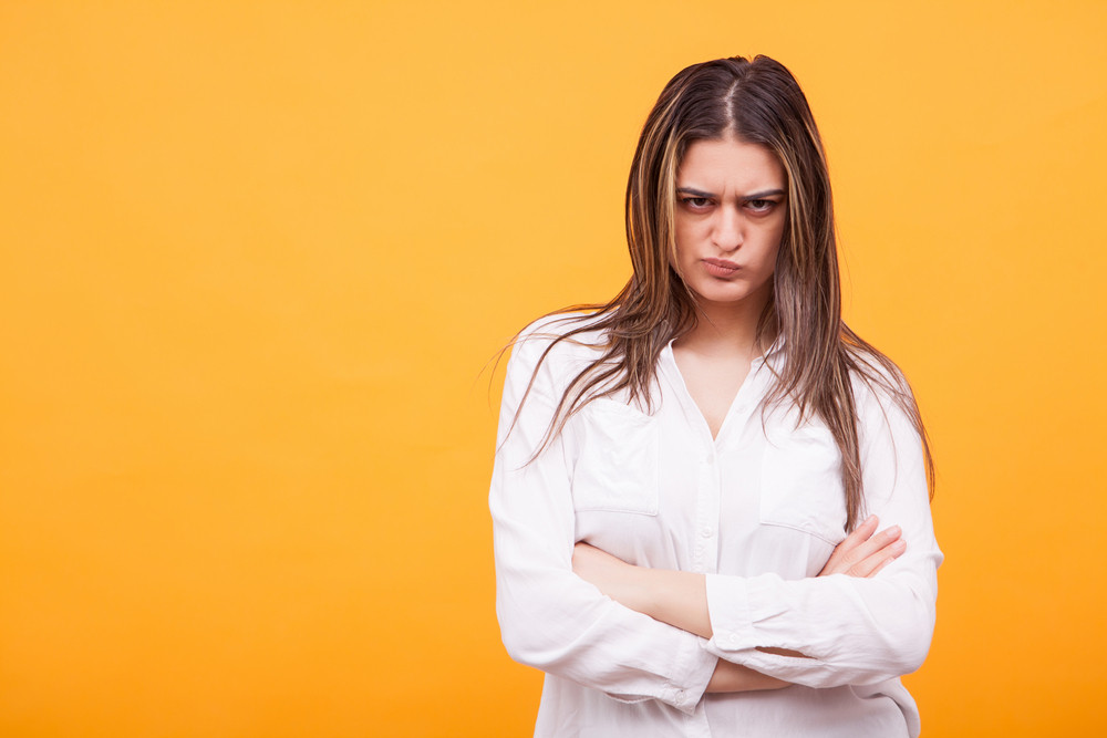 Upset young woman casualy dressed standing over yellow background